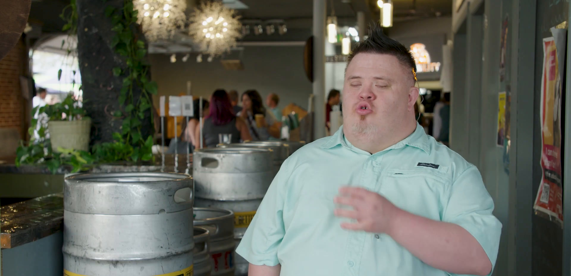 José in a mint green polo shirt beside the beer kegs, mid-conversation.